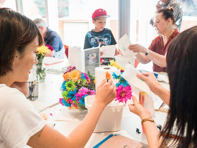 Adults and children working on an art project making flowers. 